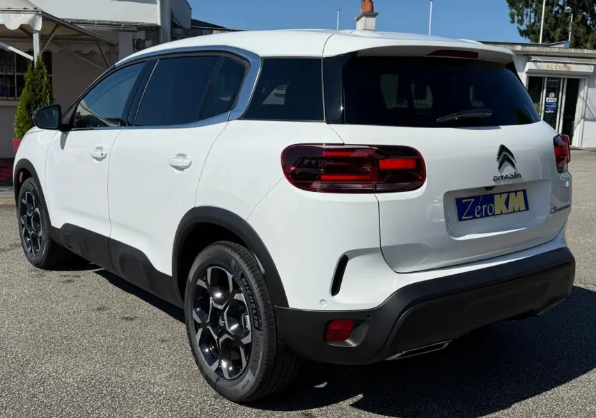 Vue 3/4 arrière droite d'un Citroën C5 Aircross blanc banquise avec jantes bi-ton et détails noirs contrastants.
