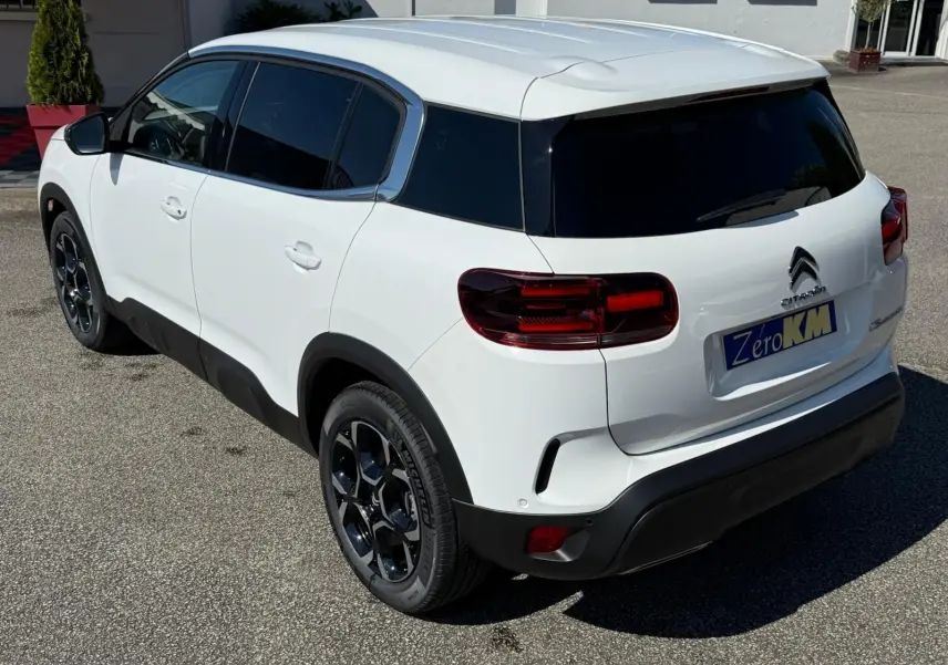 Vue 3/4 arrière droite du Citroën C5 Aircross blanc banquise avec jantes noires et vitres teintées.