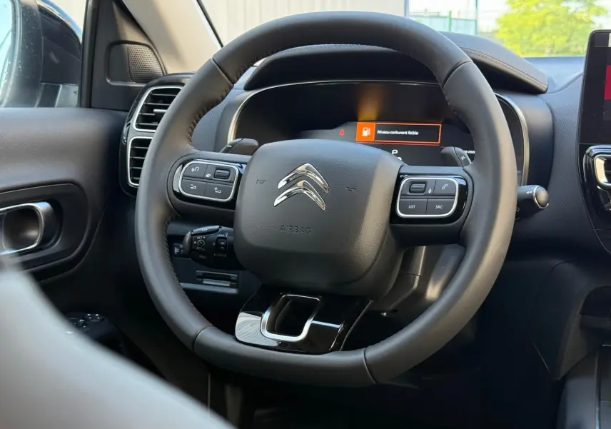 Volant multifonction noir de Citroën C5 Aircross 2024 hybride, vue rapprochée de l'intérieur côté conducteur.
