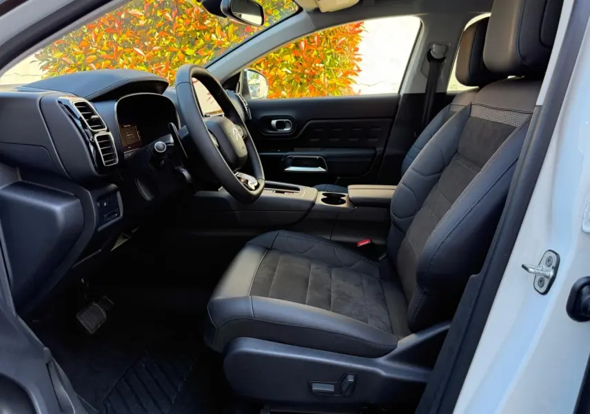Intérieur côté conducteur du Citroën C5 Aircross blanc banquise 2024, sièges cuir et alcantara noirs avec tableau de bord moderne.
