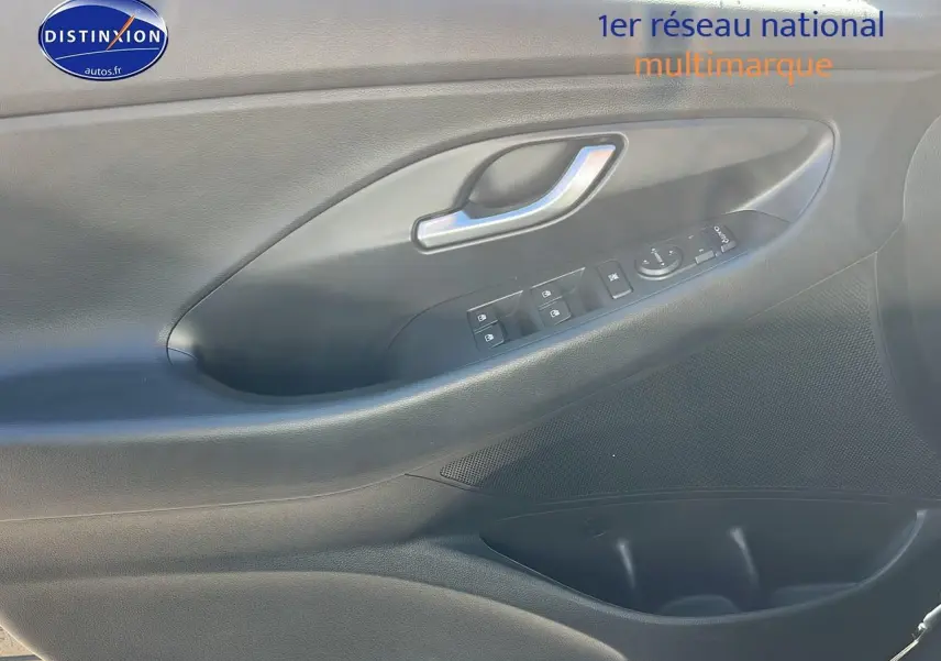 Gros plan sur la porte côté gauche intérieure grise avec commandes électriques et poignée argentée d'une Hyundai i30 2024