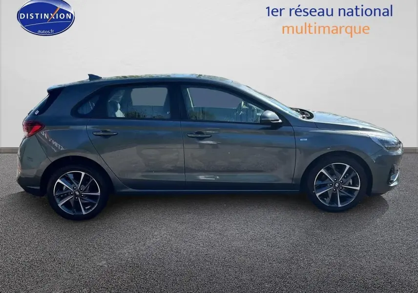 Profil droit d'une Hyundai i30 gris argent 2024 avec jantes alliage et vitres légèrement teintées.