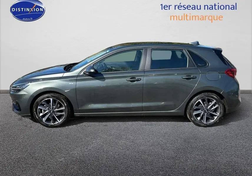 Profil côté gauche d'une Hyundai i30 gris argent 2024, avec jantes alliage et lignes épurées sur fond neutre.