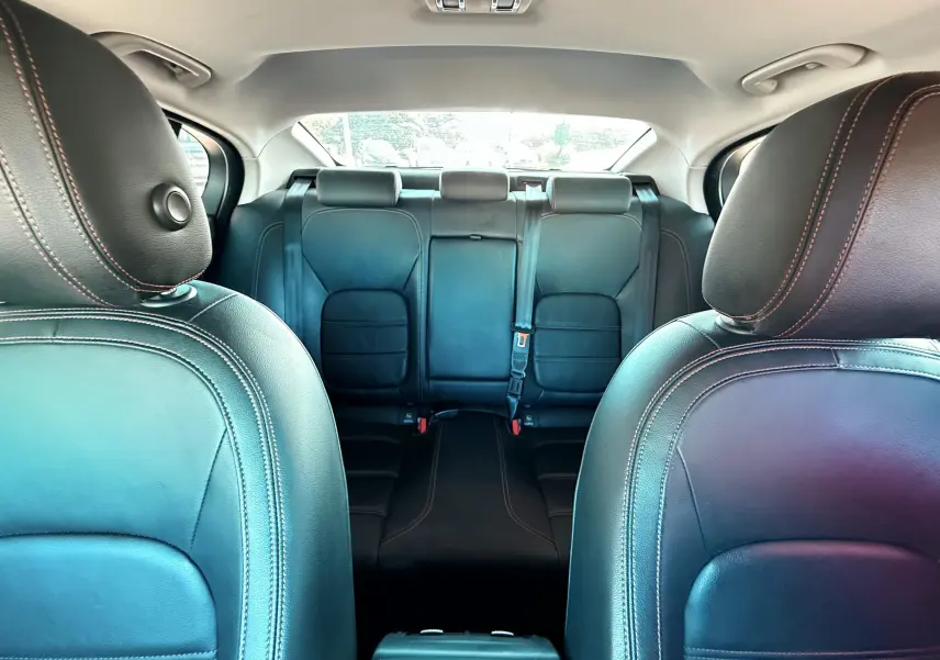 Vue intérieure montrant les sièges avant et arrière en cuir noir avec surpiqûres contrastantes d'une Jaguar XE 2019.
