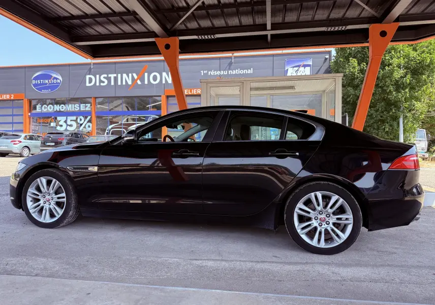 Profil côté gauche d'une Jaguar XE noire de 2019, sous un abri avec jantes alliage et lignes élégantes.