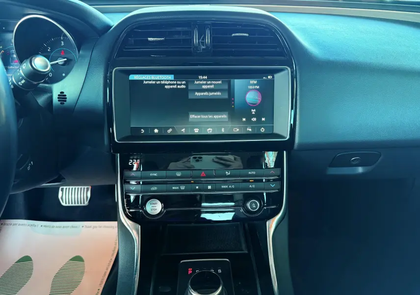 Vue centrée sur la console centrale et tableau de bord noir du Jaguar XE 2.0D 2019 avec écran tactile et commandes climatisation.