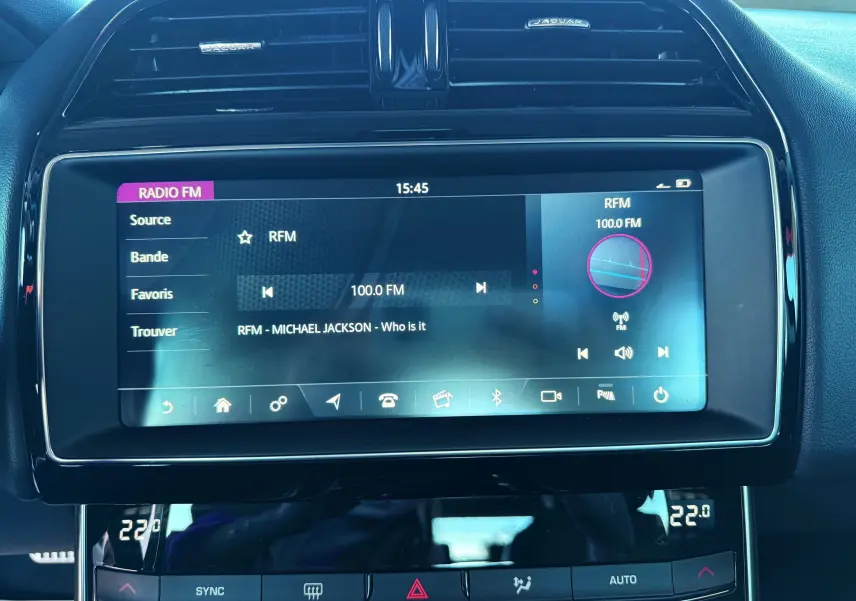 Écran tactile central de la Jaguar XE 2019 affichant la radio FM avec interface moderne et finition noire brillante.