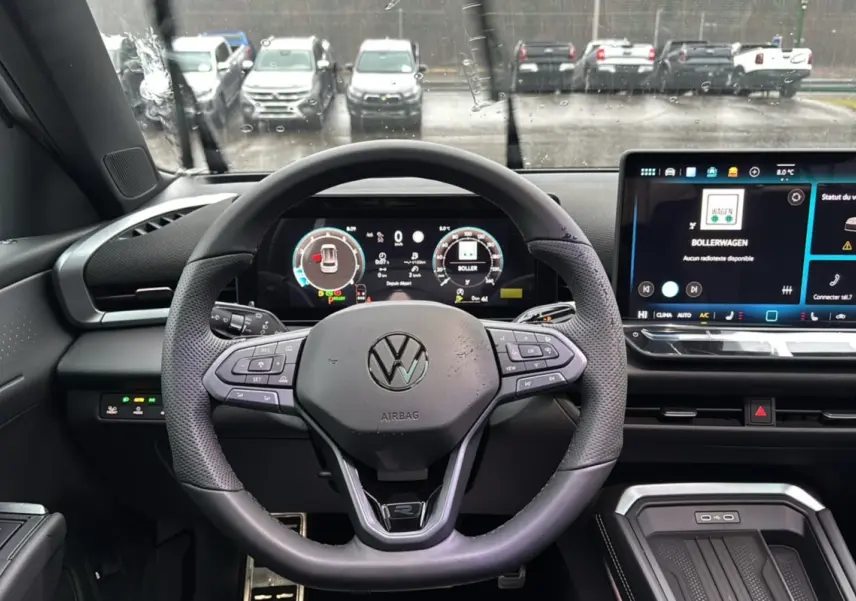 Vue intérieure centrée sur le volant cuir multifonctions d’un Volkswagen T-Roc 2026 avec tableau de bord digital et écran tactile.