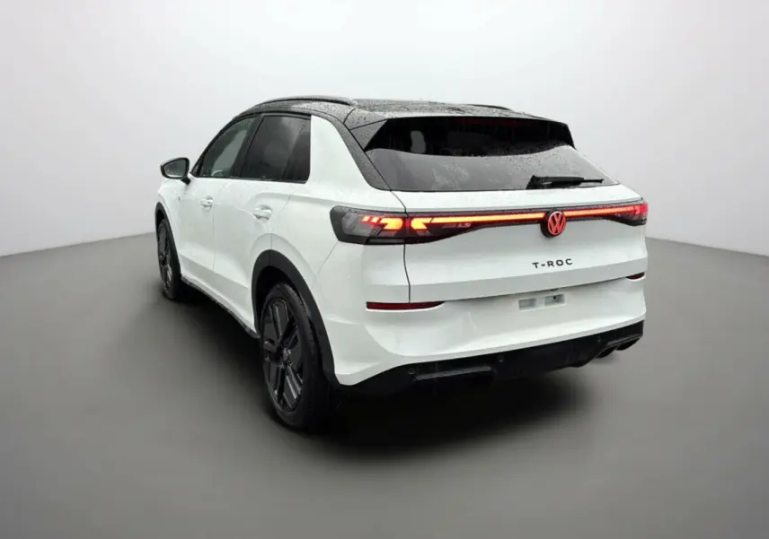 Volkswagen T-Roc blanc toit noir vu 3/4 arrière droit avec feux arrière LED allumés et jantes noires.