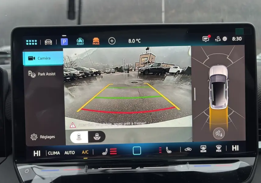 Écran intérieur affichant la caméra de recul et l’aide au stationnement du Volkswagen T-Roc blanc toit noir.