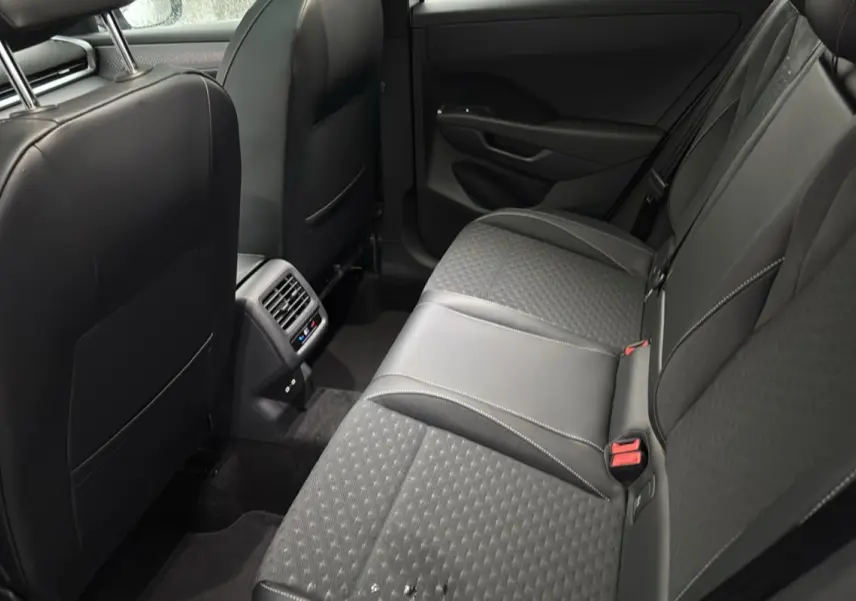 Vue intérieure arrière du Volkswagen T-Roc 2026, sièges tissu noir avec surpiqûres et aérateurs centraux visibles.
