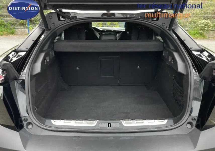 Coffre ouvert vu de l'arrière d'une Peugeot 408 Hybrid 145ch GT noir métal, montrant l'espace de chargement vide.