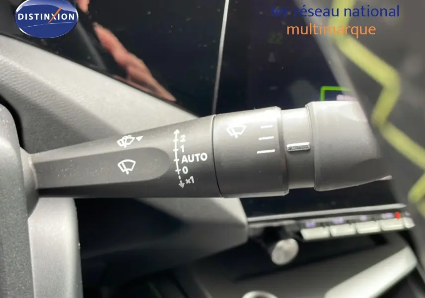Gros plan sur la commande des essuie-glaces à gauche du volant dans l’habitacle d’une Peugeot 408 noir métal 2024 hybride.