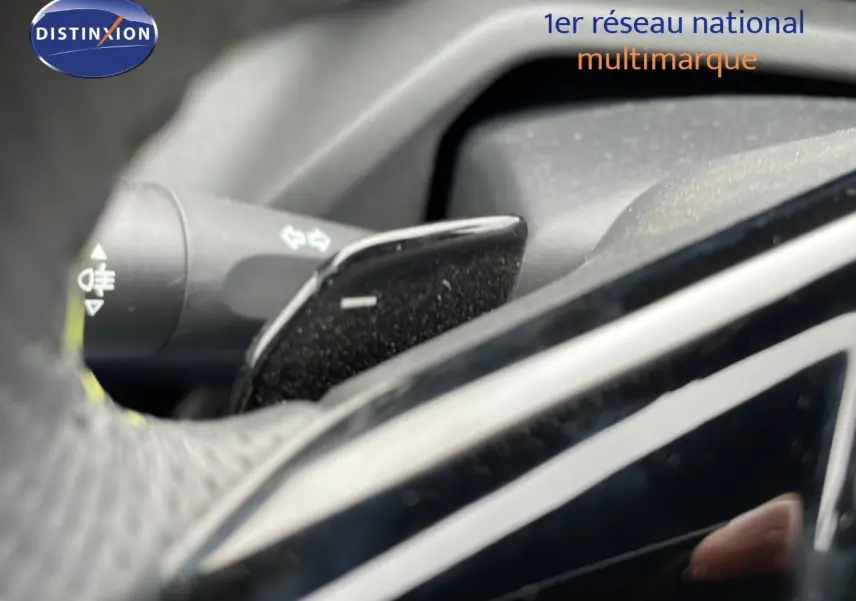 Détail du levier de clignotant et palette de commande derrière le volant d'une Peugeot 408 Hybrid noir métal 2024.