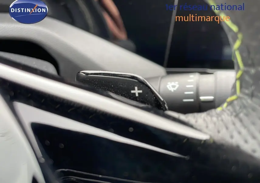 Gros plan sur la palette de changement de vitesse + du volant en cuir noir avec surpiqûres jaunes d'une Peugeot 408 HYBRID 2024.