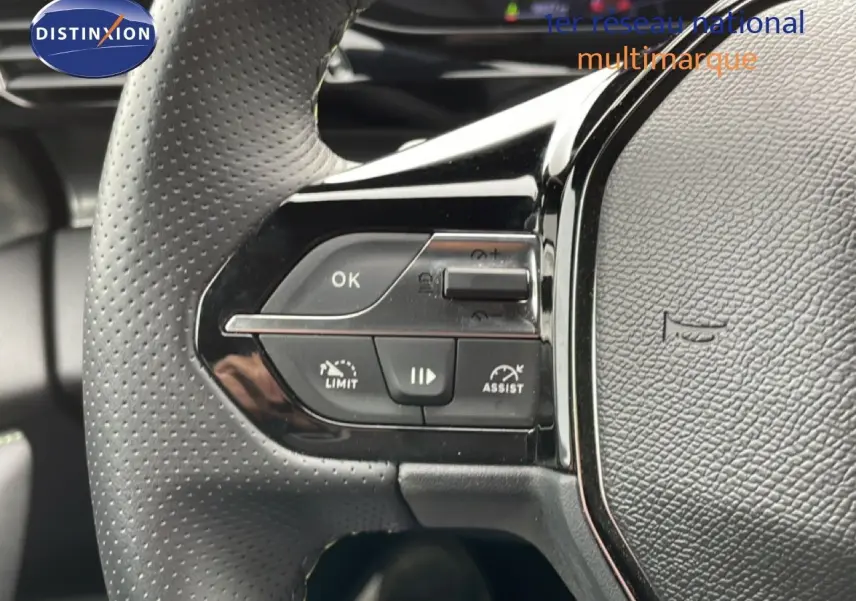 Gros plan sur la partie gauche du volant noir perforé du Peugeot 408 Hybrid 145ch 2024 avec commandes intégrées.