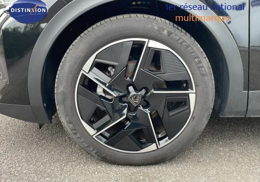 Gros plan sur la roue avant droite d'une Peugeot 408 HYBRID 145CH e-DCS6 GT noire métal avec jante au design moderne.