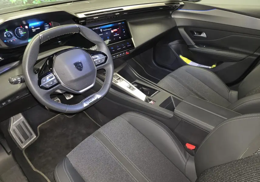 Vue intérieure côté conducteur de la Peugeot 408 gris, avec tableau de bord numérique et volant cuir perforé.