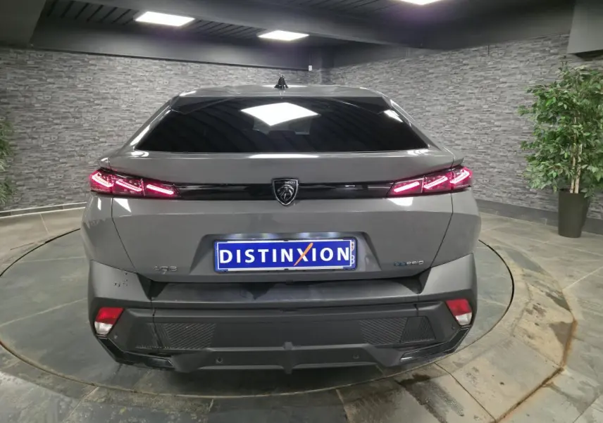 Vue arrière d'une Peugeot 408 gris métallisé avec feux arrière LED en forme de griffes et hayon électrique.