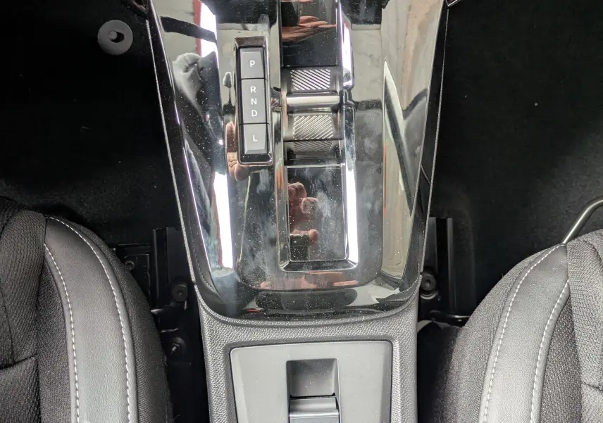 Vue plongeante sur la console centrale noire brillante avec levier de vitesses automatique et frein à main électrique du Citroën C3 Aircross.