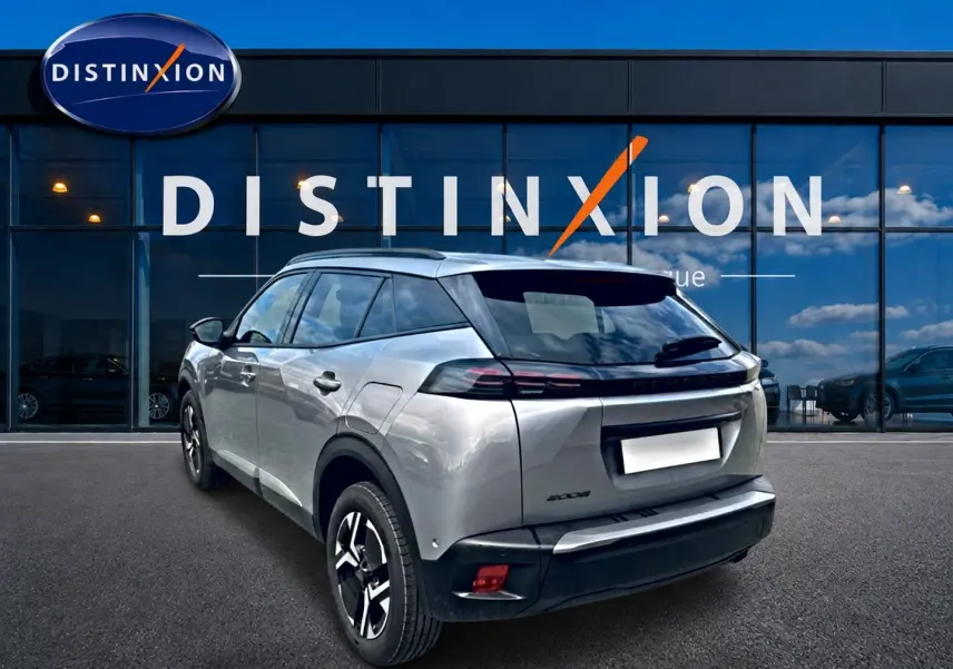 Peugeot 2008 gris artense en 3/4 arrière droit, avec jantes alu et feux arrière LED devant showroom Distinxion.