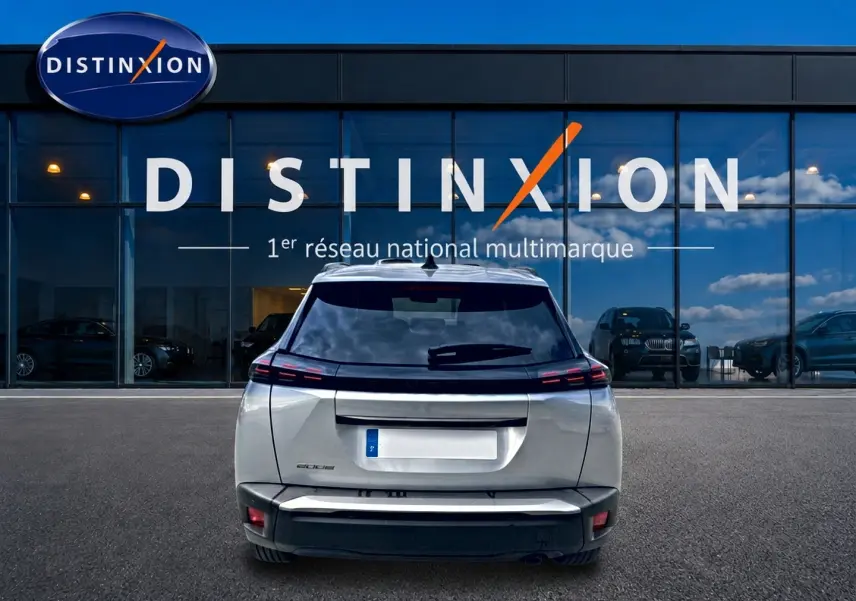 Vue arrière d'un Peugeot 2008 gris artense garé devant une vitrine avec logo Distinxion.