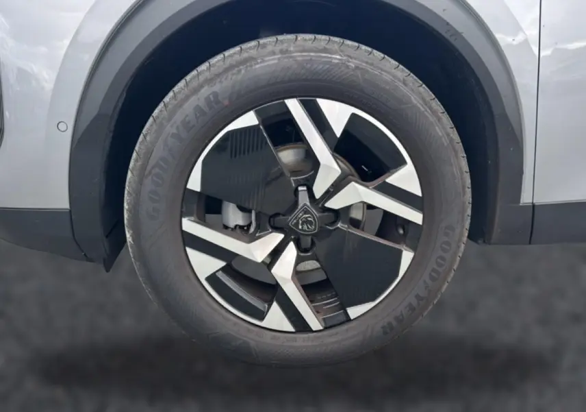 Gros plan sur la roue avant droite gris artense du Peugeot 2008 1.2 100 allure avec jante alu bicolore et pneu Goodyear.