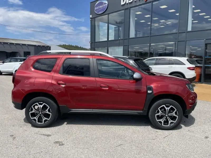 Profil droit du Dacia Duster TCE 150 Prestige 4x2 rouge métal de 2020 avec jantes alliage et barres de toit argentées.
