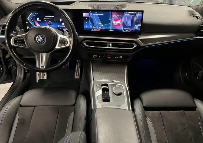 Vue intérieure avant de la BMW Série 3 G21 M Sport 320e noire, tableau de bord numérique et console centrale moderne.