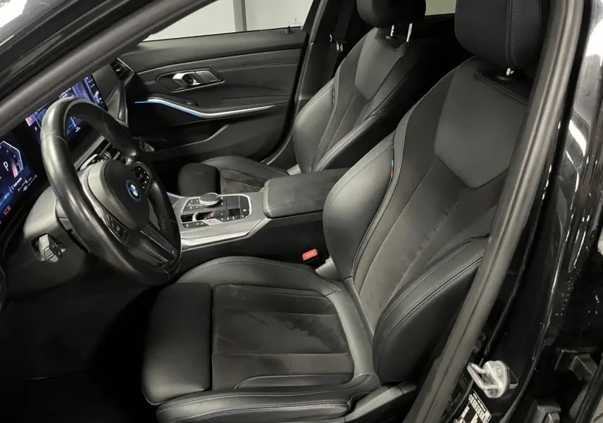 Intérieur avant droit de la BMW Série 3 320e Touring noir, sièges sport M en cuir et alcantara avec surpiqûres bleues.