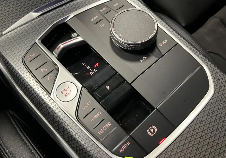 Gros plan sur la console centrale noire avec commandes de boîte auto et modes hybride de la BMW Série 3 Touring.