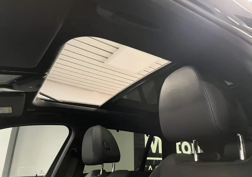 Toit ouvrant panoramique en verre vu de l'intérieur avant de la BMW Série 3 Touring noire 320e M Sport 2022