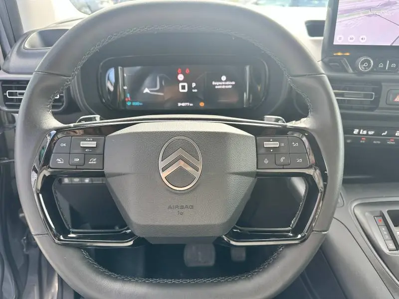 Vue rapprochée du volant cuir multifonction noir du Citroën Berlingo 2024 avec tableau de bord digital et écran tactile visible à droite