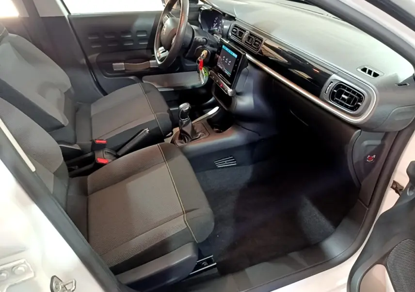 Intérieur avant droit de la Citroën C3 blanche 2020, montrant sièges tissu noirs et tableau de bord avec écran tactile.