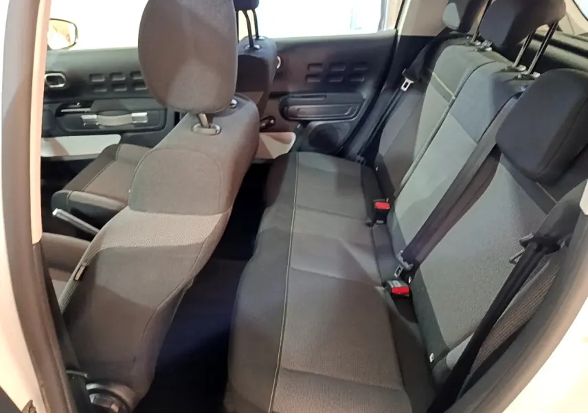Vue intérieure côté droit montrant la banquette arrière grise et les sièges avant du Citroën C3 blanc 2020.