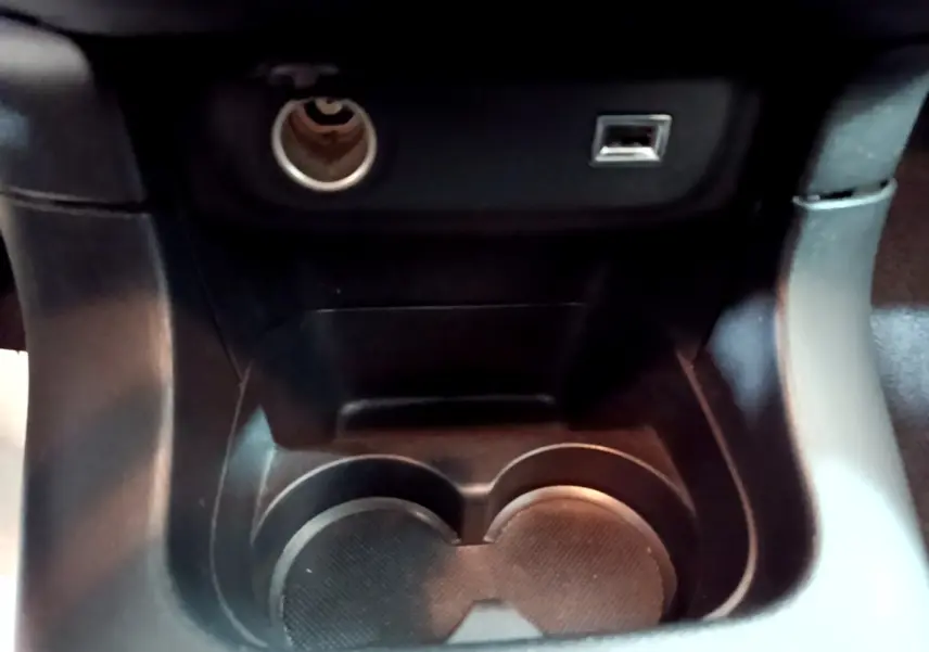 Gros plan sur la console centrale noire de la Citroën C3 avec prise allume-cigare et port USB visibles.