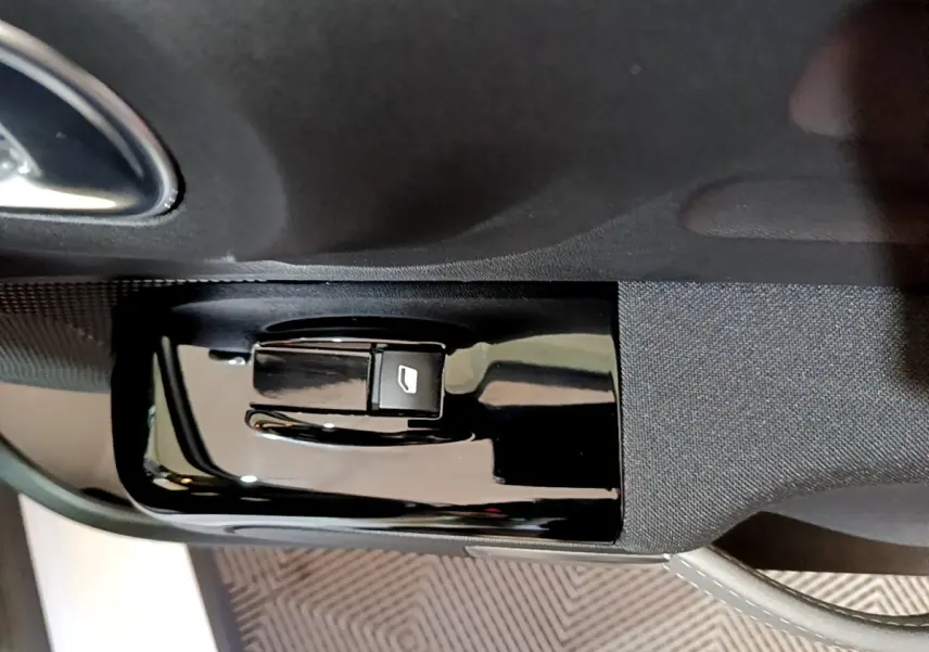 Bouton de commande de lève-vitre sur la portière côté conducteur d'une Citroën C3 blanche, vue rapprochée intérieure.