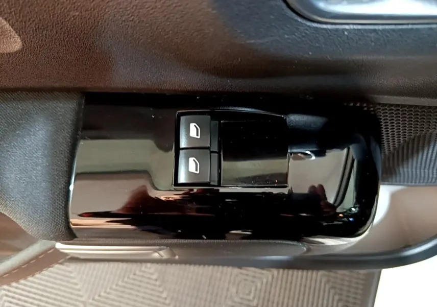 Gros plan sur les commandes de lève-vitres électriques côté conducteur dans l’habitacle noir de la Citroën C3 blanche.
