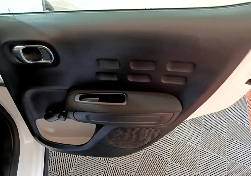 Vue rapprochée de la porte avant gauche intérieure noire et beige d’une Citroën C3 blanche de 2020.