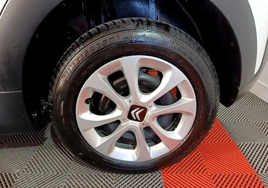 Gros plan sur la roue avant droite d'une Citroën C3 blanche, mettant en valeur la jante argentée à cinq branches.