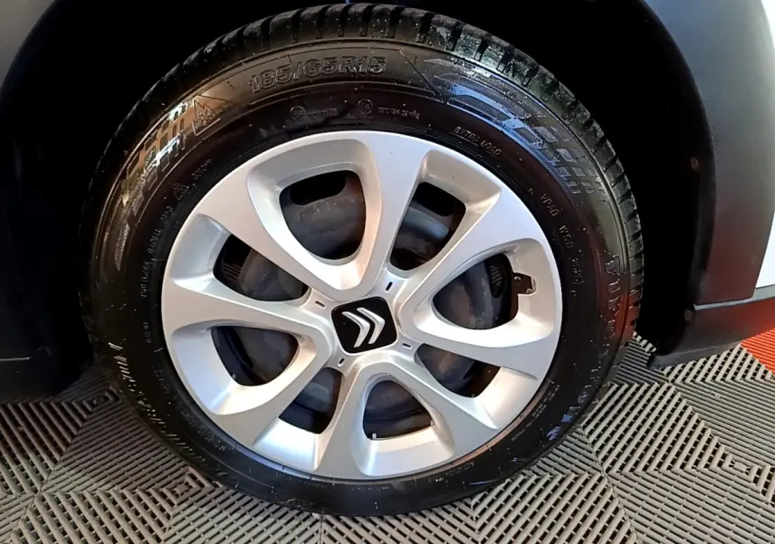 Gros plan sur la roue avant droite d'une Citroën C3 blanche, mettant en valeur la jante argentée au design moderne.