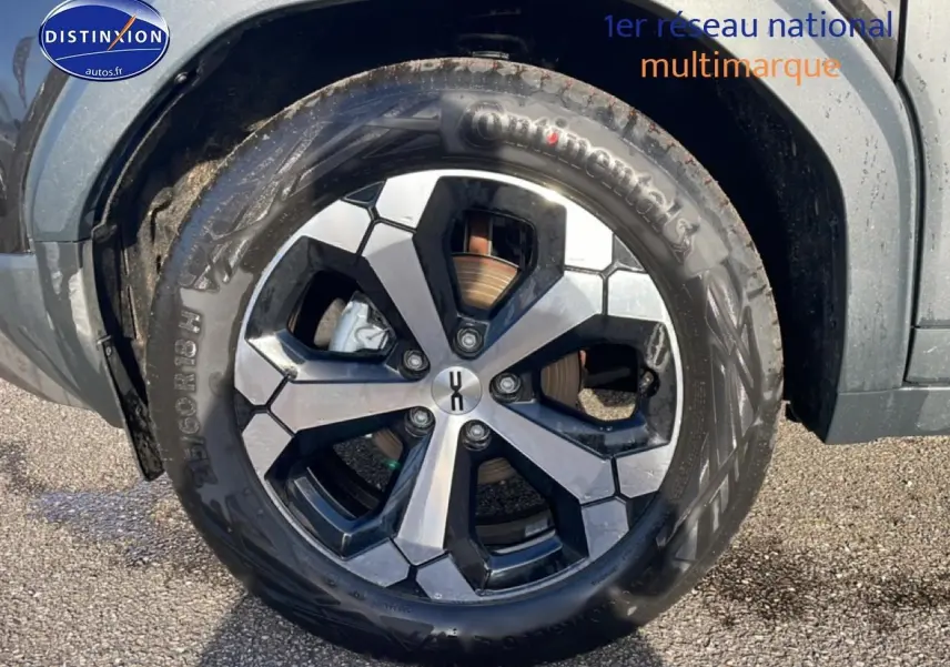 Gros plan sur la roue avant gauche du Dacia Duster noir avec jante alliage à design hexagonal.