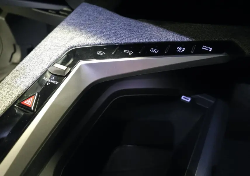 Gros plan sur la console centrale tissu gris chiné du Peugeot 3008 Hybrid 2025 avec commandes tactiles et prise USB-C.