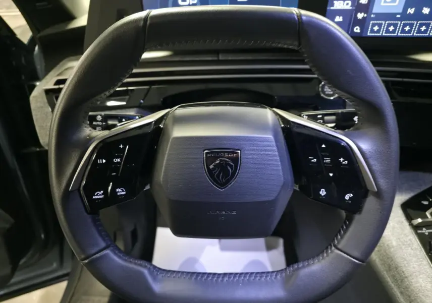 Vue rapprochée du volant noir cuir du Peugeot 3008 2025 avec commandes intégrées et logo lion central.