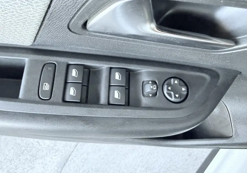 Gros plan sur les commandes de lève-vitres et rétroviseurs sur la porte côté gauche d'une Citroën C4 blanche.