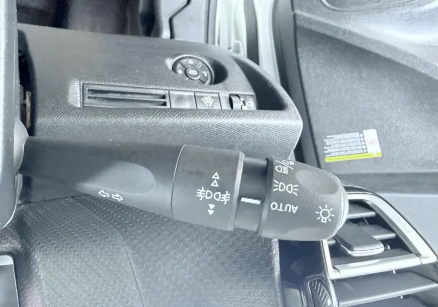 Gros plan sur la commande des phares et clignotants côté gauche du tableau de bord d'une Citroën C4 blanche 2023.