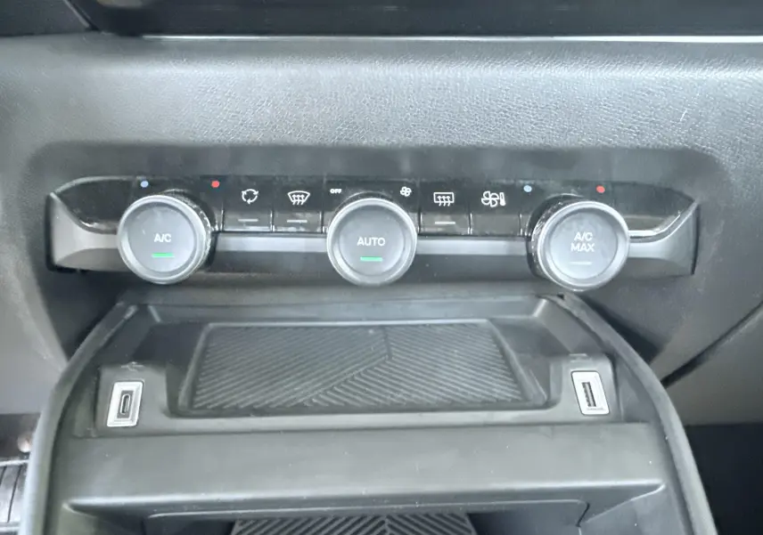 Vue rapprochée du tableau de commande de climatisation avec trois boutons rotatifs sur une Citroën C4 blanche de 2023.
