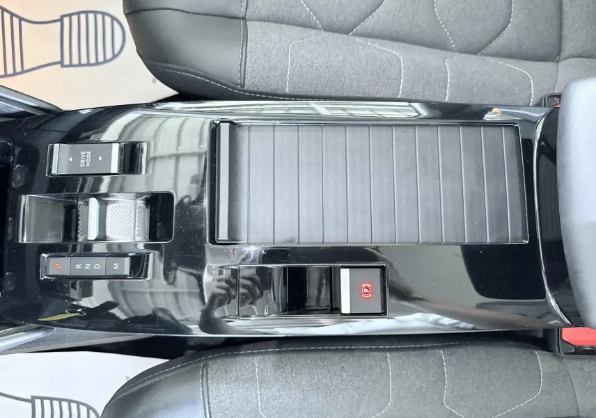 Vue plongeante sur la console centrale noire brillante de la Citroën C4 avec levier de vitesse automatique et bouton frein à main électrique.