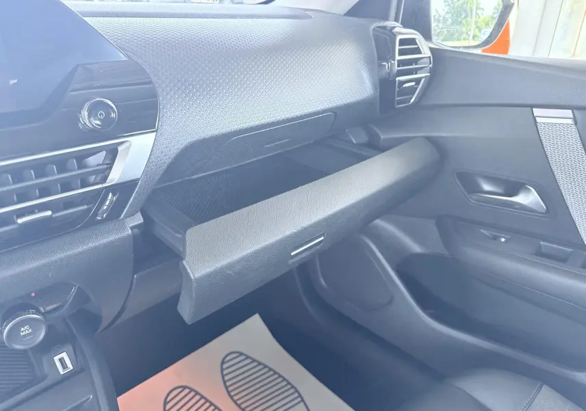 Intérieur avant droit de la Citroën C4 2023 avec boîte à gants ouverte et tableau de bord noir texturé.