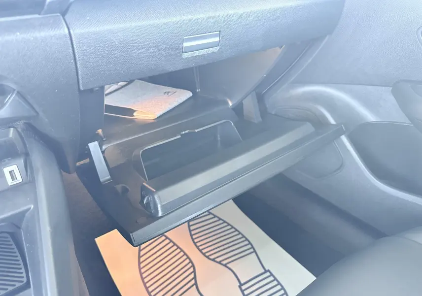 Vue intérieure du coffre à gants ouvert côté passager du Citroën C4 1.5 HDI blanc, montrant le rangement et le tapis de sol.